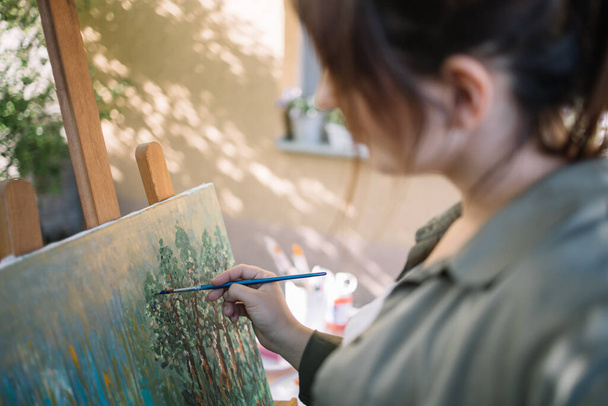 Blurred brunette woman painting picture in yard - Fotó, kép