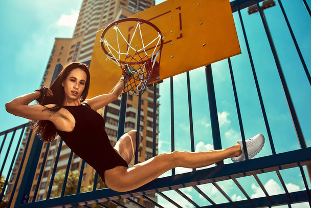 Strong and sexy sportive woman training outdoors, on the ground. jumped to the basketball basket - Foto, immagini