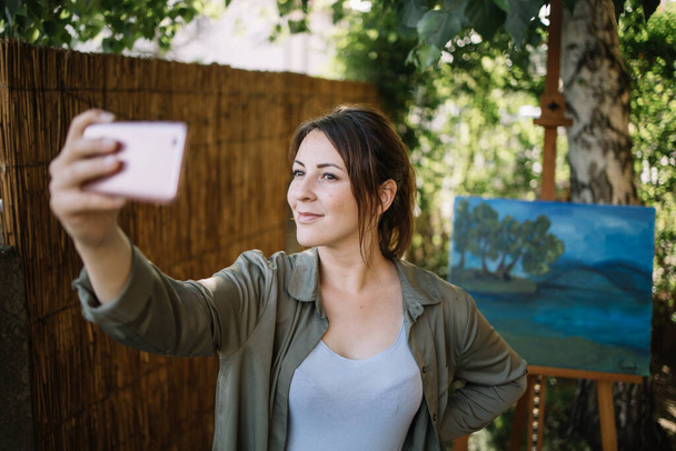 Kobieta robi selfie przed malowaniem na podwórku - Zdjęcie, obraz
