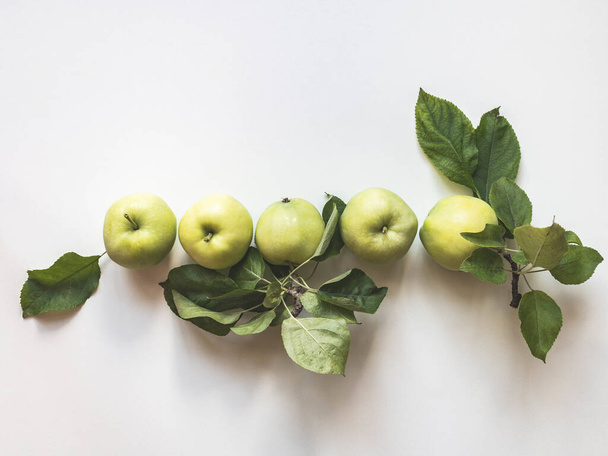 Composição de maçãs verdes e folhas em um fundo branco. Papel de parede de frutas.Vista superior, flat lay
. - Foto, Imagem