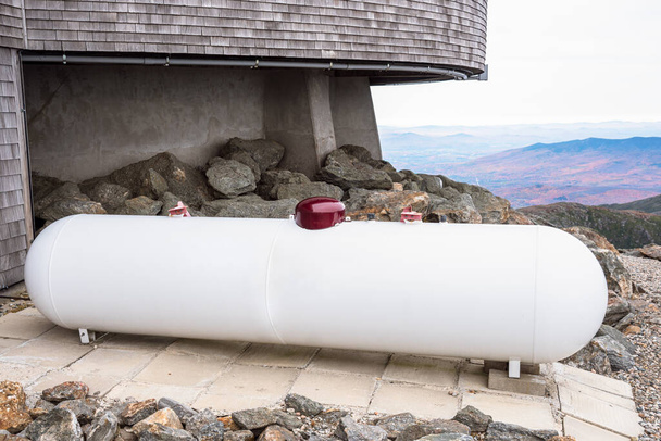 Un jour d'automne nuageux, un grand réservoir de propane blanc recouvre l'arrière d'un bâtiment situé au sommet d'une montagne. Mount Washington, NH, États-Unis. - Photo, image