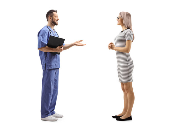 Full length profile shot of a male healthcare workers having a conversation with a young female patient isolated on white background - Photo, image