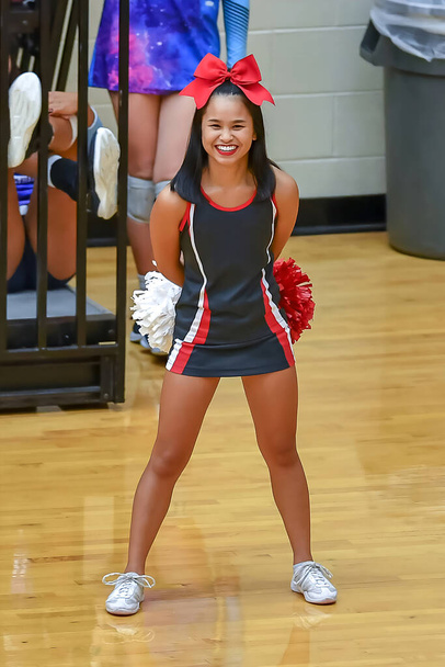 carino asiatico americano cheerleader esecuzione a un liceo gioco - Foto, immagini