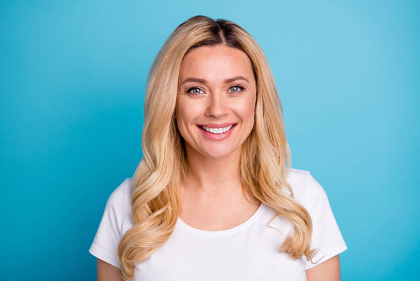 Closeup photo of attractive lady wavy blond hairdo confident smile cheerful charming person wear casual white s-shirt isolated blue color background - Valokuva, kuva