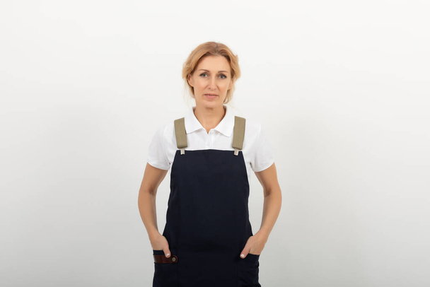 Ritratto di donna commessa o piccolo negoziante che indossa al grembiule in piedi su sfondo chiaro. agenzia di pulizia fornisce i suoi servizi - Foto, immagini