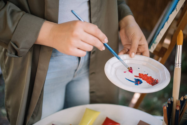 Mujeres manos mezclando pinturas en la placa usando cepillo
 - Foto, imagen