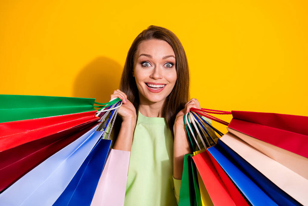 Photo of charming shocked lady good mood street look hold many shopping bags open mouth cool sales wear green sweatshirt isolated vivid bright yellow color background - Foto, Bild