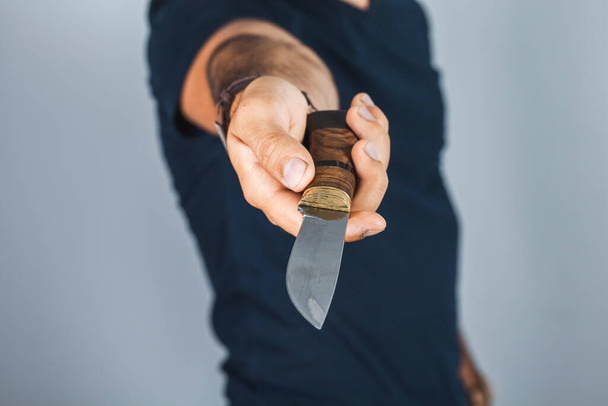 Hand of caucasian man holding a knife isolated on a gray background - Photo, Image