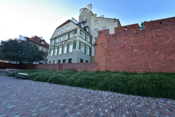 The historic defensive walls of the Warsaw Barbican and burgher houses in the Old Town in the light of the rising sun. Summer. - Photo, Image