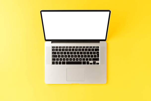 Portátil con pantalla vacía sobre fondo amarillo. Concepto de escritorio de oficina. Vista superior
 - Foto, imagen