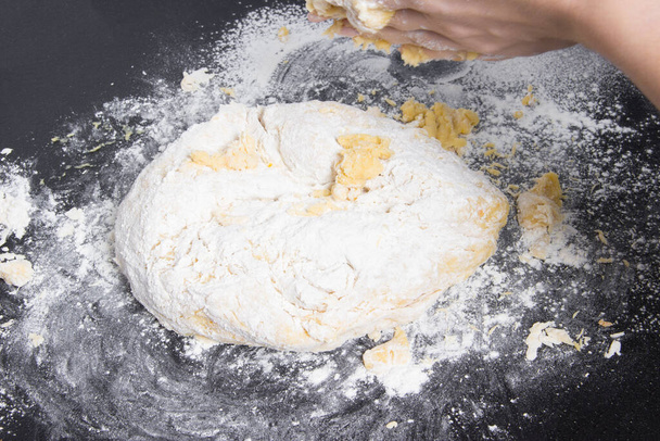 pâte fraîche prête à cuire avec les mains de la femme sur la table noire. - Photo, image