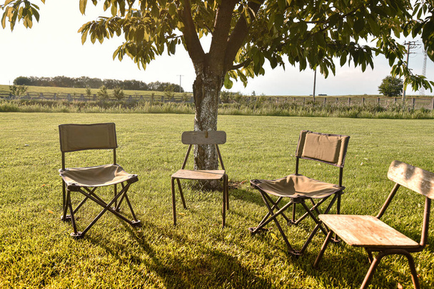 Vier Klappstühle für Angeln und Entspannung im Freien stehen unter einem Baum - Foto, Bild