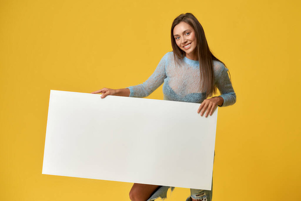 Joyful girl holding blank cardboard poster - Φωτογραφία, εικόνα