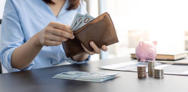 Empresario con un bolso marrón y un billete de 100 dólares, ahorrando dinero y gastando usando el concepto de efectivo
. - Foto, imagen