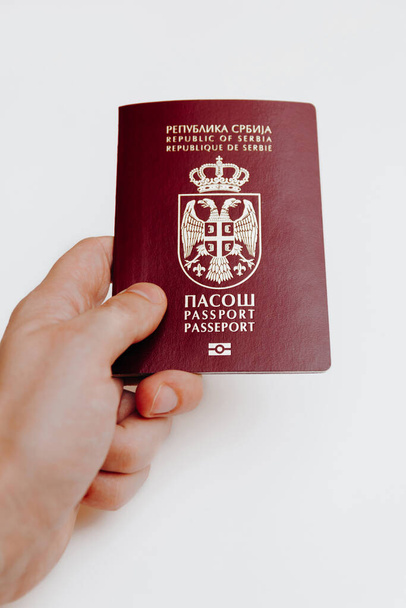 Κρατούσε το σερβικό βιομετρικό διαβατήριο, απομονωμένο σε λευκό φόντο - Φωτογραφία, εικόνα