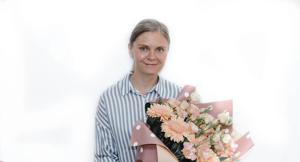young woman in a striped blue blouse holds a huge bouquet of orange gerbera rose flowers. birthday gift to the woman.  - Photo, Image