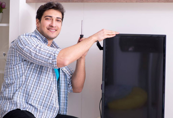 Uomo che ripara la tv rotta a casa - Foto, immagini