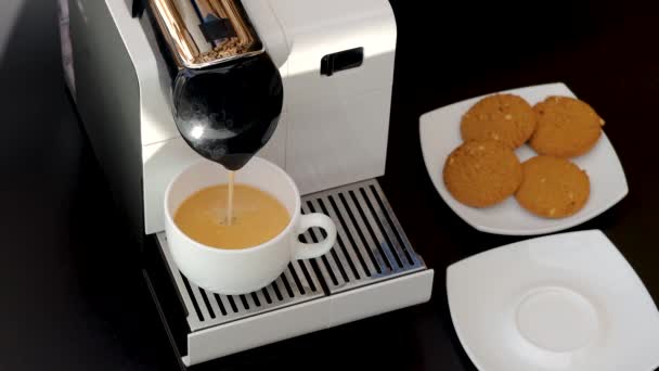 Nahaufnahme des Kaffees, der aus der Kapselkaffeemaschine in die weiße Tasse läuft. Schöne Hintergründe. - Filmmaterial, Video