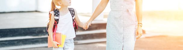 Mom holding her child s hand, mom meets her child from school, back to school. - Photo, Image
