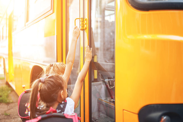 Des écolières avec des sacs à dos entrent dans le bus scolaire, retournent à l'école. - Photo, image