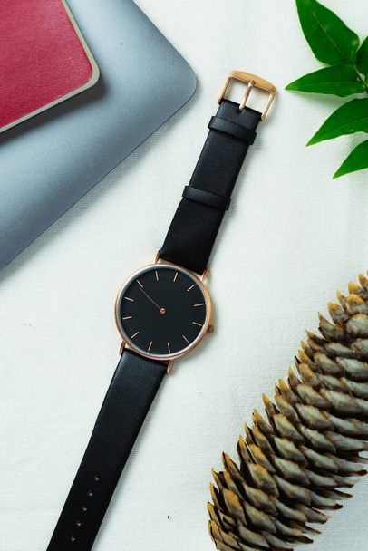 Detailní minimální módní náramkové hodinky pro unisex na bílém pozadí s květinami a počítačem - Fotografie, Obrázek