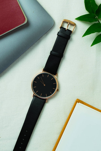 Closeup minimal fashion wristwatch for unisex on white background with flowers and computer - Fotó, kép