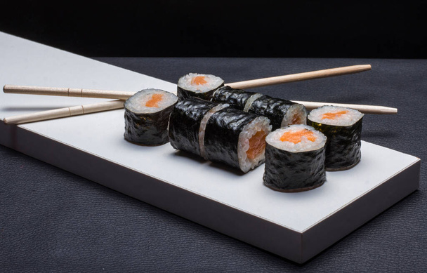 伝統的な箸で白い盆の上に海苔で包んだ日本料理のおにぎり. - 写真・画像