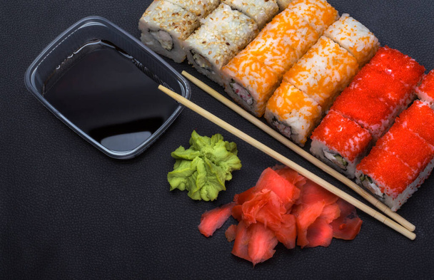 Японская кухня рисовые рулеты с традиционными палочками для еды и васаби с имбирем, вид сверху. - Фото, изображение