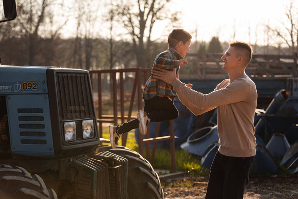 батько зі своїм маленьким сином добре проводить час на фермі біля тракторів у сонячний осінній день. день батька
. - Фото, зображення