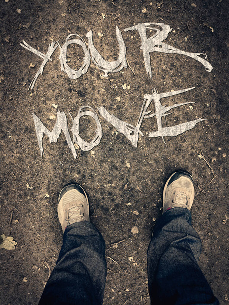 Plakat motywacyjny z napisem "twój ruch". Nogi w butach widok z góry. Konceptualna pisemna wiadomość o posunięciu naprzód. Pierwszy rzut oka na buty na ziemi. Grunge motywacyjne pisanie. - Zdjęcie, obraz