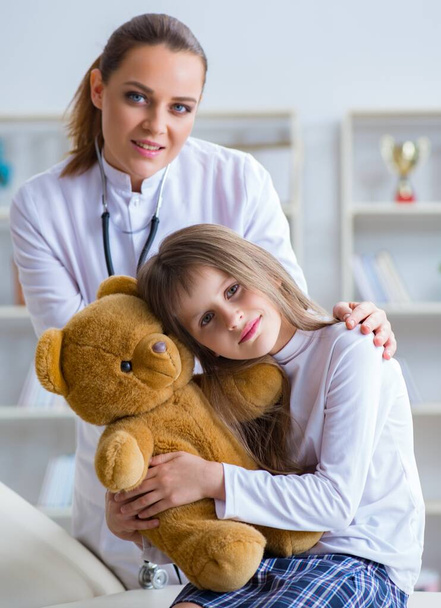 Žena žena lékař vyšetřuje malou roztomilou dívku s medvídkem - Fotografie, Obrázek