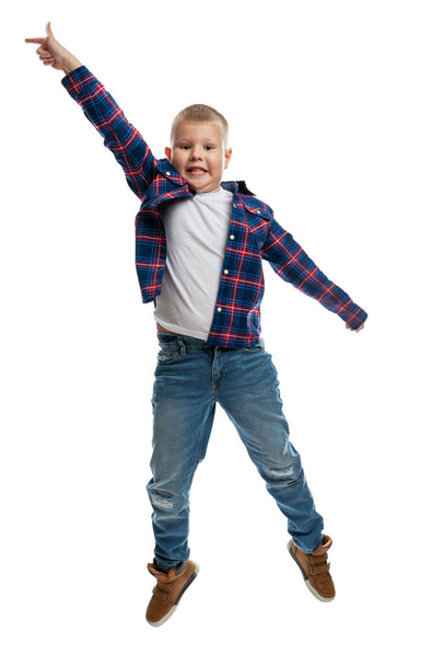The boy is jumping. Fat schoolboy in jeans and a shirt. Energy and movement. Isolated on white background. Vertical. - Fotografie, Obrázek
