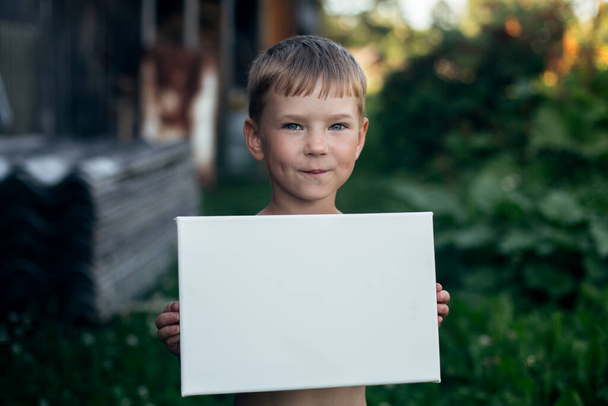 Kleiner Junge hält sauberes weißes Blatt Papier (Banner für Botschaft) - Foto, Bild