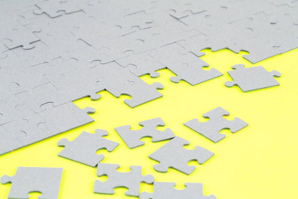 Unfinished jigsaw puzzle pieces on yellow background. - Photo, Image