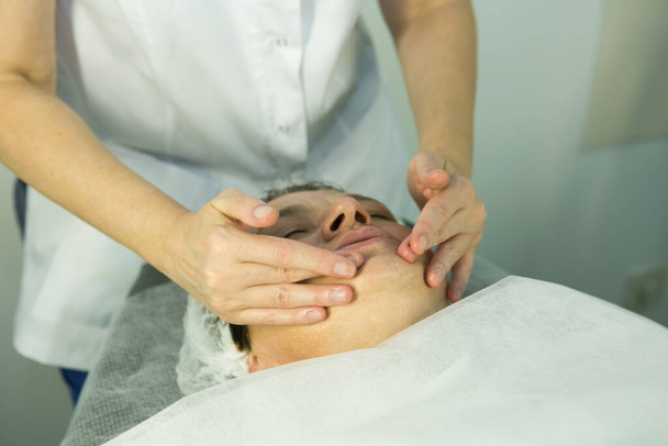 Uma visita ao esteticista. Procedimento-carboxiterapia. Médico cosmetologista faz massagem facial do paciente após o procedimento
. - Foto, Imagem