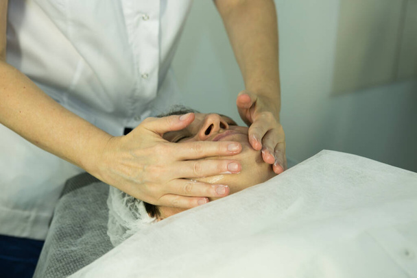 Una visita dall'estetista. Procedura-carbossiterapia. Il cosmetologo medico fa il massaggio facciale del paziente dopo la procedura. - Foto, immagini