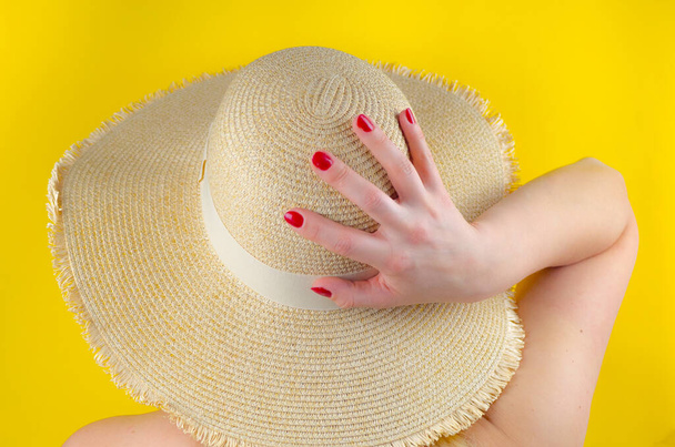 κορίτσι σε ψάθινο καπέλο σε κίτρινο φόντο, έντονα κόκκινα βαμμένα χείλη. - Φωτογραφία, εικόνα