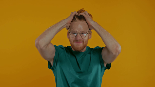 angry redhead man in glasses screaming isolated on yellow - Imágenes, Vídeo