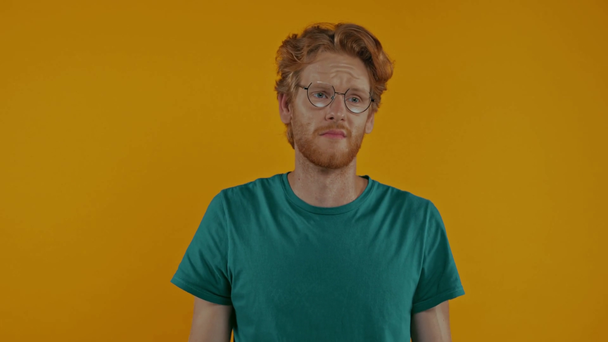 smutny rudzielec w okularach mówi na smartfonie odizolowany na żółty - Materiał filmowy, wideo
