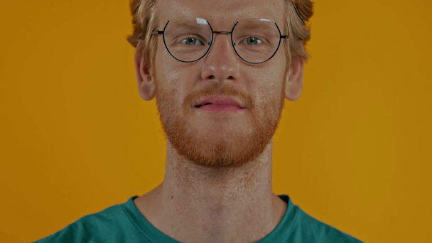 portrét usmívajícího se zrzavého muže v brýlích izolovaných na žluté - Záběry, video
