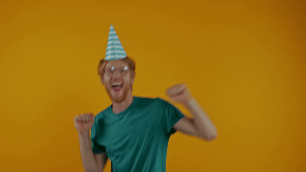 happy redhead man in party cap dancing isolated on yellow - Footage, Video