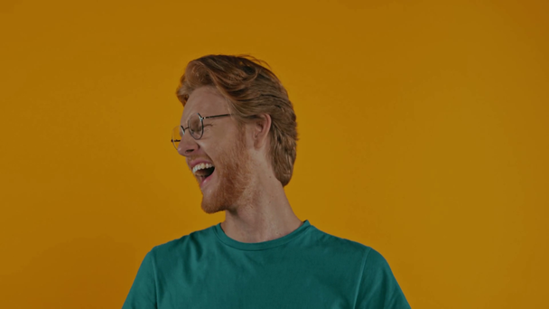 onnellinen punapää mies lasit nauraa eristetty keltainen - Materiaali, video