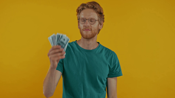 幸せな赤毛の男は貯金箱を揺らし黄色で隔離されたお金は - 映像、動画