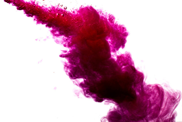 A cloud of red paint is released into the clear water. Isolate on a white background. - Photo, image