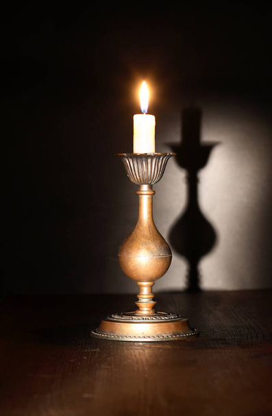 Eleganter Kerzenständer aus Messing mit brennender Kerze auf dunklem Hintergrund - Foto, Bild