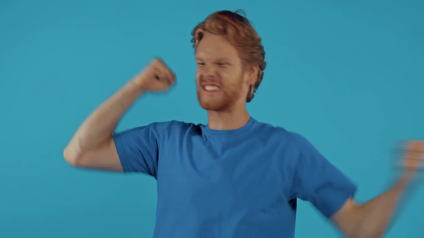 angry bearded redhead man screaming isolated on blue - Video, Çekim