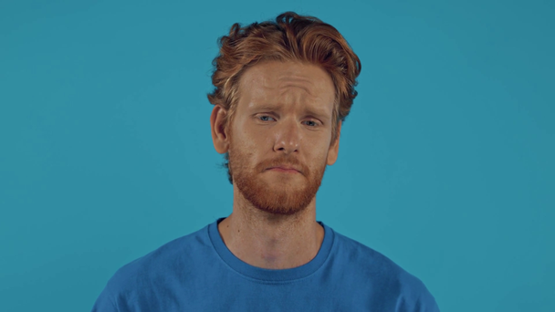 surullinen parrakas punapää mies eristetty sininen - Materiaali, video