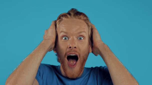 Shocked bearded redhead man isolated on blue - Кадры, видео