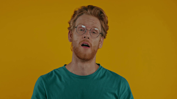 sleepy redhead man in glasses yawning isolated on yellow - Footage, Video