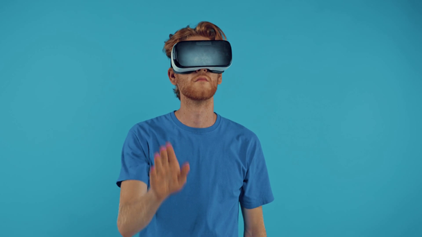 γενειοφόρος κοκκινομάλλης gesturing σε vr ακουστικά που απομονώνονται σε μπλε - Πλάνα, βίντεο